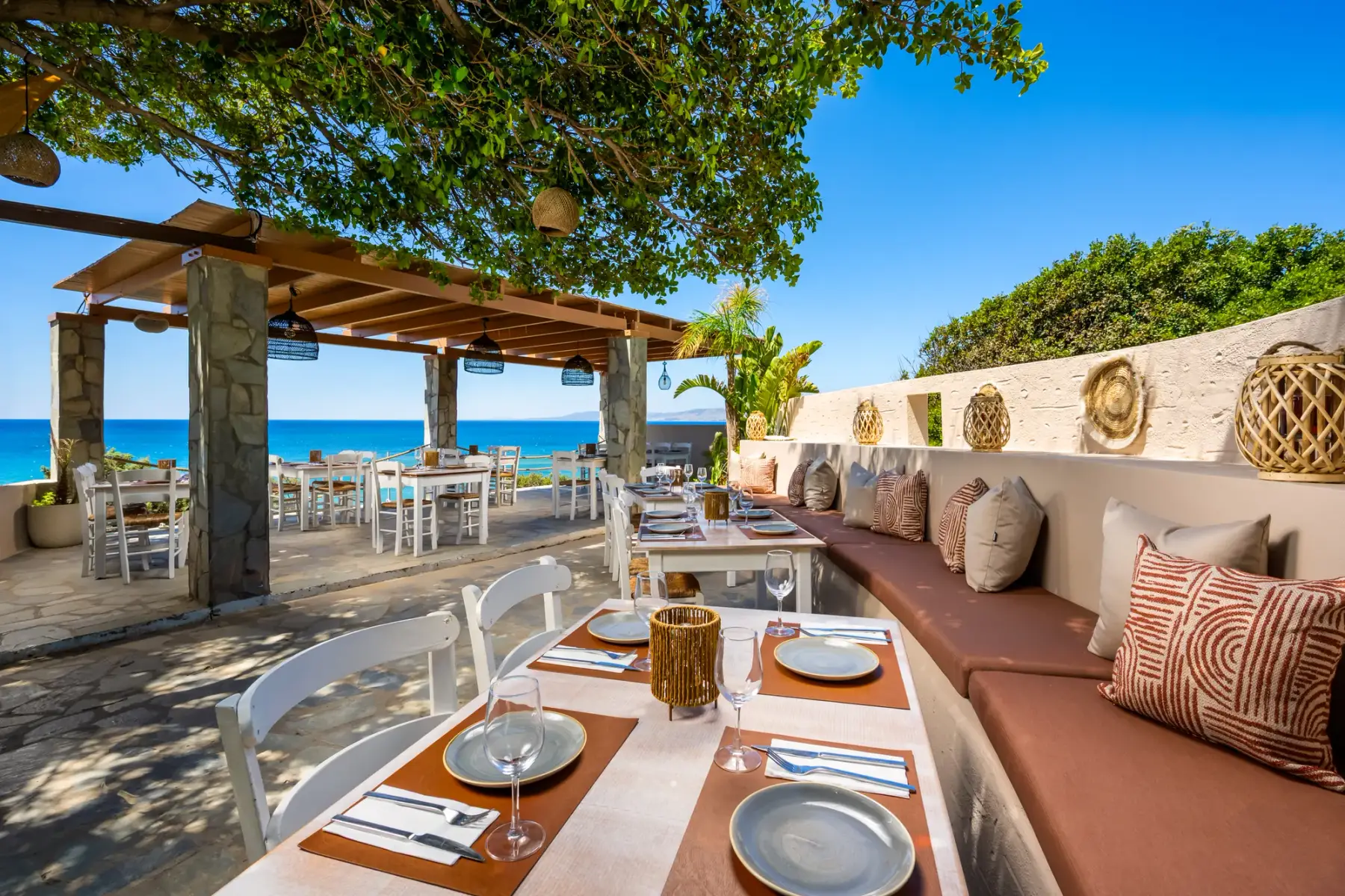 Shaded dining terrace under a tree at Parea Sea Side